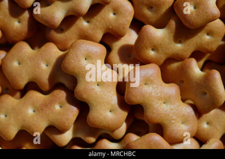 A huge bunch of salted biscuits of small sizes close-up. Macro shot of a large amount of salt cracker in golden yellow tones Stock Photo