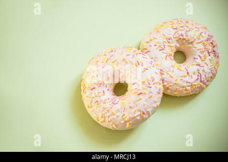 Assorted donuts isolated. Tasty donuts with colorful sprinkles on light soft green background. Sweet and colorful dessert. Copy space Stock Photo
