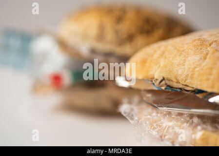 Fresh tasty burger with plastic waste and paper cardboard inside on white background. Recycled waste in our food concept. Stock Photo