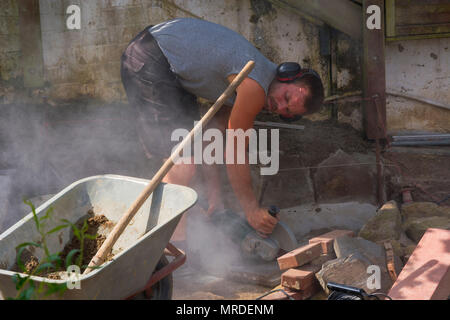 Worker cuts the bricks with a cut-off grinder. Stock Photo