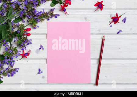 White tabletop with spring flowers, blank pink paper and a pencil Stock Photo