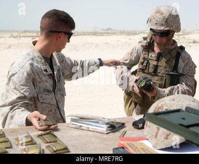 U.S. Marine Corps Cpl. Reagan Schmidt, an ammunition technician with Marine Wing Support Squadron 372, Special Purpose Marine Air-Ground Task Force-Crisis Response-Central Command, hands pistol ammunition to U.S. Marine Corps Lance Cpl. Joseph Lenhard, a tactical switching operator with MWSS-372, SPMAGTF-CR-CC, during a weapons transition range in the Middle East, May 28, 2017. This sustainment range offered an opportunity for the Marines to practice tactical transitions from an M4 carbine to an M9 pistol, ensuring SPMAGTF Marines are prepared to react and respond to a variety of scenarios tha Stock Photo