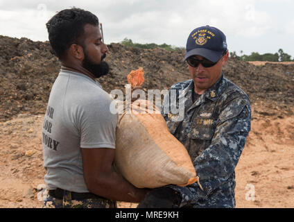USS Lake Erie (CG 70) is a Ticonderoga-class guided-missile cruiser operated by the United States Navy within the U.S. 7th Fleet area of responsibility. The archival image records a chief petty officer from the ship working with Sri Lankan Marines on levee repairs in Matara on June 12, 2017, during humanitarian assistance efforts after monsoon flooding and landslides. Stock Photo