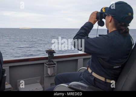 170610-N-ZW825-222 SOUTH CHINA SEA (June 10, 2017) Cmdr. Claudine Caluori, commanding officer of Arleigh Burke-class guided-missile destroyer USS Sterett (DDG 104) observes Japan Maritime Self-Defense Force (JMSDF) ship JS Izumo (DDH 183) off Sterett’s starboard side. Sterett, Izumo, JMSDF ship JS Sazanami (DD 113), Royal Canadian Navy ship HMCS Winnipeg (338) and Royal Australian Navy ship HMAS Ballarat (FFH 155) conducted a series of maritime operations together in the South China Sea. Sterett is part of the Sterett-Dewey Surface Action Group and is the third deploying group operating under  Stock Photo