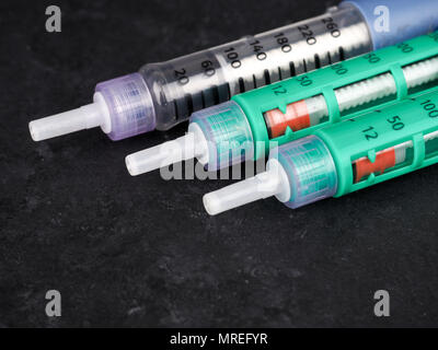 medicine, diabetes, advertisement and health care concept - close up of glucometer with blood sugar test stripe, insulin injection syringes and pills  Stock Photo