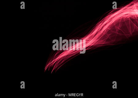 Light painted glowing abstract light red and pink curved lines on a black background Stock Photo