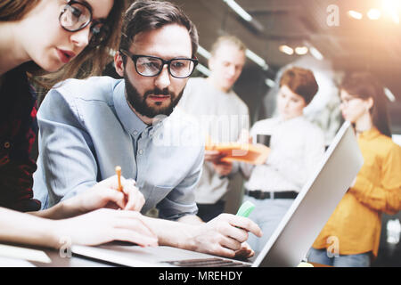 Young team of people works together on a new project in a modern loft office. Create a new concept. Working at laptop and paperwork. Group of coworker Stock Photo