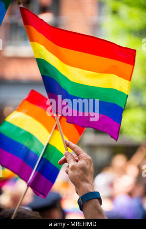 Rainbow flags flying in bright sun on the sidelines of a colorful summer gay pride parade Stock Photo