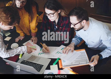 Group of students female and male discussing diagrams and graphs. Team of engineers looks at the results of the experiments. Brainstorming ideas conce Stock Photo