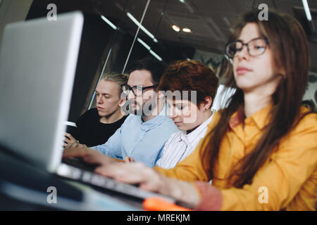 Working atmosphere in a modern coworking room. Crew of young male and female architects creating new plan Stock Photo