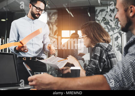 Marketing group discussing new product plan. Young businesspeople working on modern devices. New startup company. Intentional lens flares Stock Photo