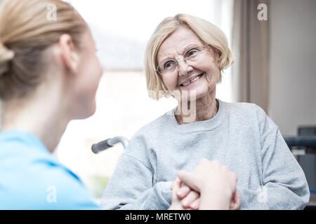 Senior woman smiling at care worker. Stock Photo