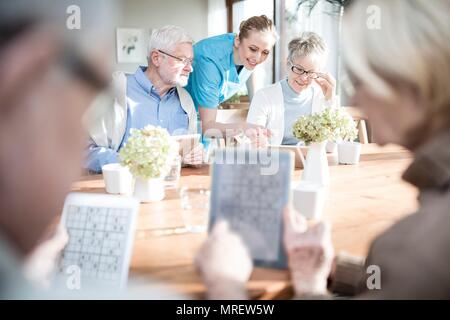 Senior adults playing games on digital tablets in care home. Stock Photo