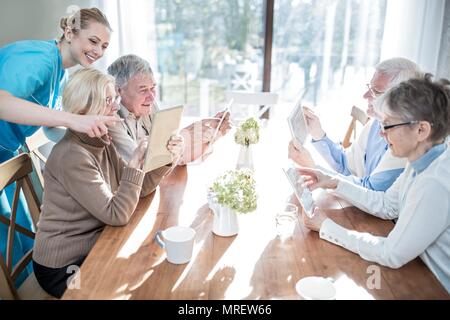 Senior adults using digital tablets in care home. Stock Photo