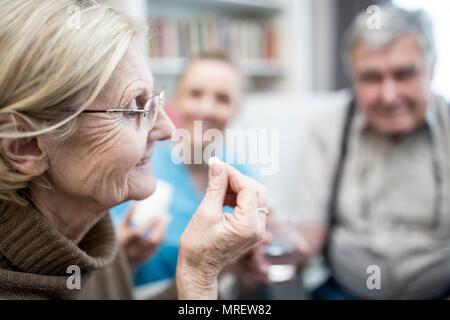 Senior woman taking tablet in care home. Stock Photo