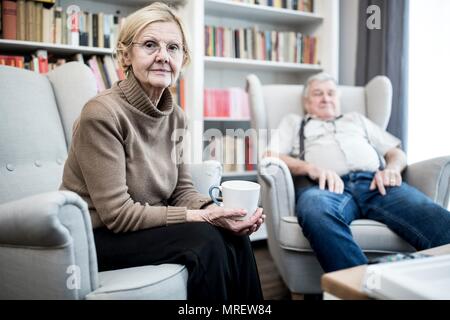 Senior couple sitting on armchairs, portrait. Stock Photo