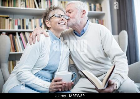 Senior man kissing woman on cheek with arm around her. Stock Photo