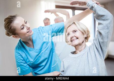 Senior woman stretching, physiotherapist helping. Stock Photo
