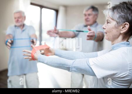 Senior adults using resistance bands in exercise class. Stock Photo