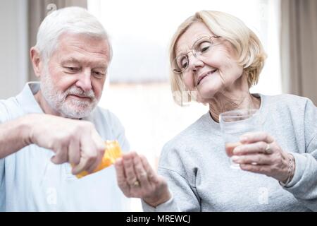 Senior man giving woman medication. Stock Photo