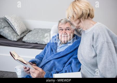 Senior couple reading book in care home. Stock Photo