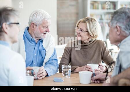 Four friends talking in retirement home. Stock Photo