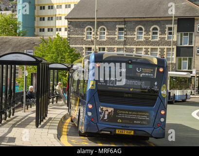 Buses stopped at a town centre bus stop with people waiting under the shelters Stock Photo