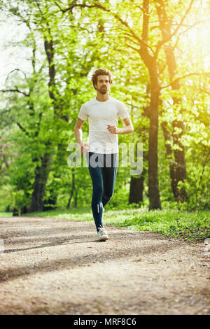 Young man is jogging in park. Stock Photo