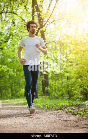 Young man is jogging in park. Stock Photo