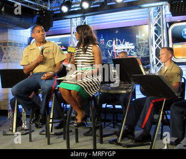 Gunnery Sgt. Justin A. Hauser, enlisted conductor of Marine Corps Band New Orleans, talks with Sharon Barnes-Waters, co-host of CityViews on 1010 Wins Radio in New York City June 13, 2017. Hauser and members of the band performed several songs live to promote various Marine Corps Reserve Centennial concerts happening June 14-16, in multiple locations across the city. U.S. Marine Corps photo by Gunnery Sgt. Elizabeth Inglese Stock Photo