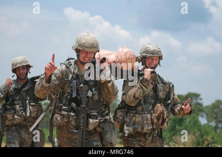 Sgt. Benjamin Poulin, a watercraft operator representing the 377th Theater Sustainment Command, Sgt. Luciano Batista, a chemical, biological, radiological, and nuclear specialist representing the 412th Theatre Engineer Command, and Pfc. Scott Smullen, a human intelligence collector representing the Military Intelligence Readiness Command, give the 'number 1' sign as they carry a mock patient to an extraction point during Mystery Event Day 4 at the 2017 U.S. Army Reserve Best Warrior Competition at Fort Bragg, N.C. June 15. This year’s Best Warrior Competition will determine the top noncommissi Stock Photo