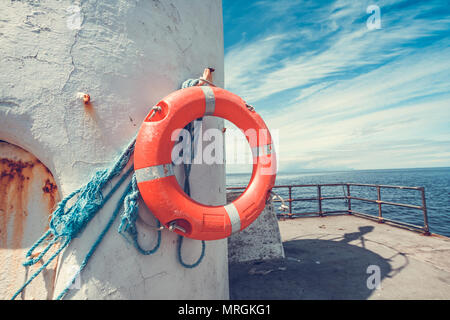 Orange lifebuoy hanged on the lighthouse with blue sky and white clouds Stock Photo