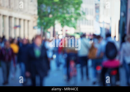 Vintage tone abstract people crowd background with blur effect applied. Unrecognizable man and woman silhouettes walking on a city street in a busy ho Stock Photo