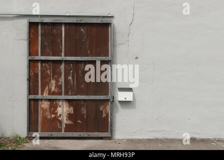 Rusty metal door against white stucco wall. Stock Photo