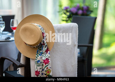 Chair with an Old Fashioned Womans Hat Hanging on it. Stock Photo
