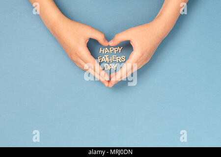 Happy Father's day card with childs hands in shape of heart an woden letters inside. Concept card. Stock Photo