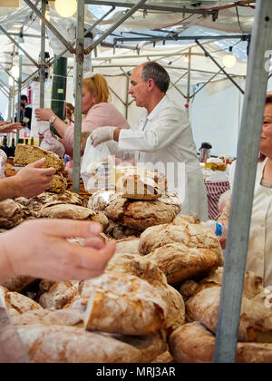 Bakers selling Hogazas, typical Spanish bread loaf, in a bakery stall at traditional market. Stock Photo