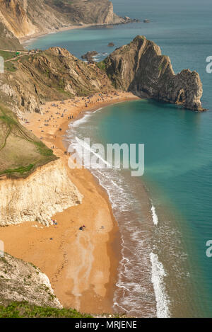 A high up view of the famous limestone arch Durdle Door and golden sand beach from the South West Coastal Path running on top of the near by cliffs, L Stock Photo