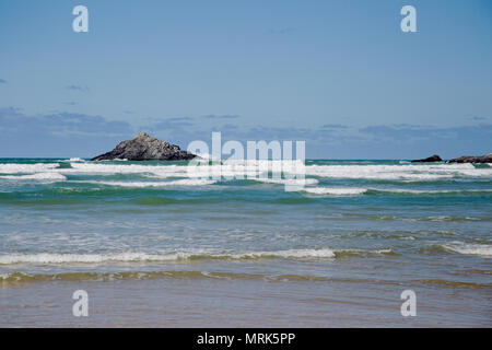 View of a rocky island seen from a Cornish beach on a sunny day Stock Photo