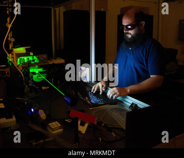 Air Force Institute of Technology is a graduate school of engineering and management operated by the United States Air Force at Wright-Patterson Air Force Base, Ohio. The archival image documents an optical engineering student working with a laser in a laboratory setting on June 21, 2017, in support of advanced research within Air Force Materiel Command. Stock Photo
