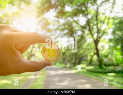 Bitcoin gold coin, Hand hold bitcoin in the park and natural background Stock Photo