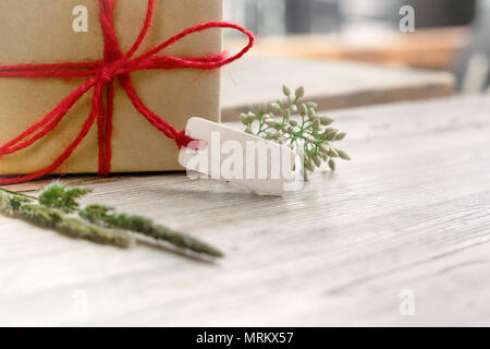 Gift box with blank tag and flower on wooden table, copy space for texting Stock Photo