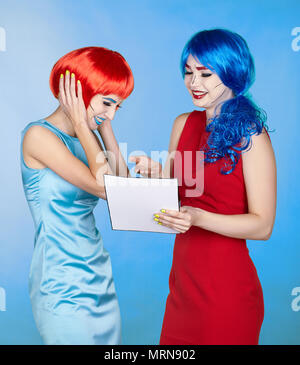 Portrait of young women in comic pop art make-up style. Females in red and blue wigs and dresses are reading letter Stock Photo