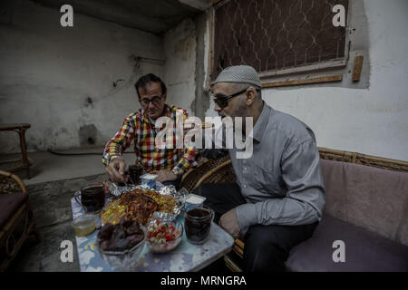 Gaza City, Gaza Strip. 26th May, 2018. Christian Kemal Terzi (L) shares an Iftar (breakfast) meal with his Muslim friend Hatem Haras, who lost his sight six years ago, in Gaza City, Gaza Strip, 26 May 2018. Since Hatem lost his sight, Terzi helps him in his daily life routine, accompanying him to mosques, markets, and share their meals together during the holy fasting month of Ramadan. Credit: Mohammed Talatene/dpa/Alamy Live News Stock Photo
