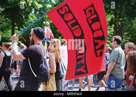 Berlin, Germany. 27th May, 2018. A man seen waving a flag writting on it 'Global Solidarity' during the protest.Techno lovers and anti racism activists have marched in Berlin against a rally organised by the German far-right party, AFD. Over 70.000 people (according to the organisers) have taken the streets of Berlin with a huge party organised by some of the most famous Berlin techno clubs. Several counter demos have taken place along the German capital to protest against the AFD rally that has started at the main train station and finished at the Brandenburger Tor with hundreds of attendant Stock Photo