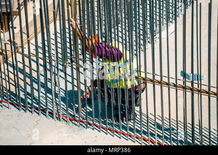 Worker measuring formwork for pouring concrete on metal rods reinforcement at construction site. Stock Photo