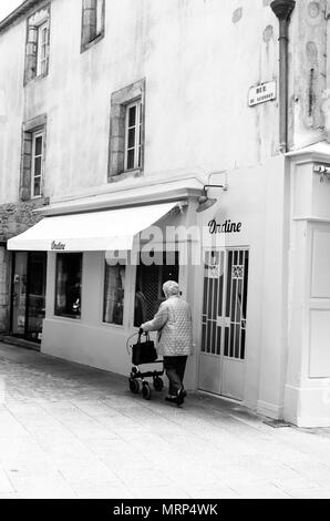 An elderly woman with a wheeled walker in a quiet street in Quimper, Brittany, France. B&W Stock Photo