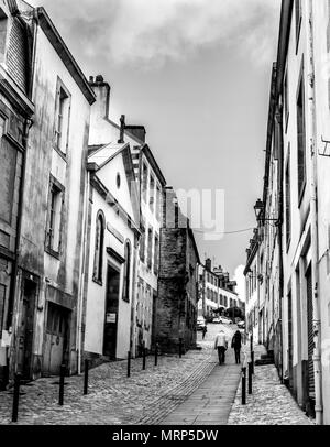 Two people walking up one of the steeper historic streets in Quimper, Brittany, France. B&W Stock Photo