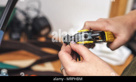 Tanner makes holes in punch in leather workpiece. Process of working in workshop close-up. Stock Photo