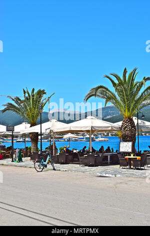 Holidaymakers enjoying a harbour-side meal in overlooking the waters of Sami on the Greek holiday island of Cephalonia or Kefalonia. Stock Photo